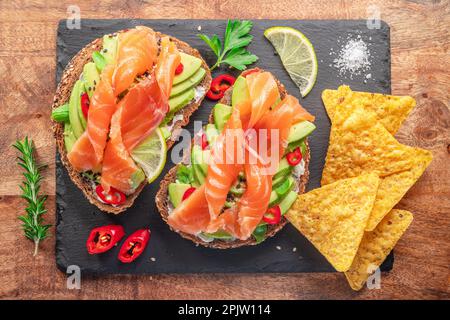 Toasts de saumon - pain avec tranches de saumon et tartinade d'avocat, guacamole et chips de tortilla. Vue de dessus. Banque D'Images