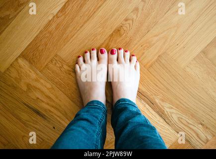 vue sur les jambes de femme pieds nus portant un jean bleu sur un sol en bois avec espace de copie Banque D'Images
