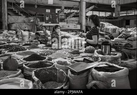 Un détenteur de contrat conclut une transaction avec un client de sa stalle vendant des haricots secs, des légumineuses et des épices sur le marché central de Pleiku, au Vietnam. Banque D'Images