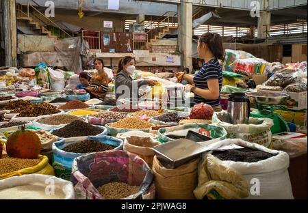 Un détenteur de contrat conclut une transaction avec un client de sa stalle vendant des haricots secs, des légumineuses et des épices sur le marché central de Pleiku, au Vietnam. Banque D'Images