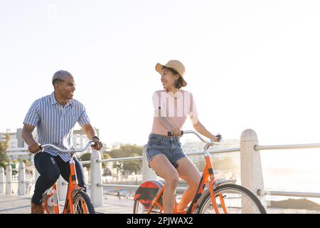 Heureux couple divers à vélo le long de la promenade au bord de la mer Banque D'Images