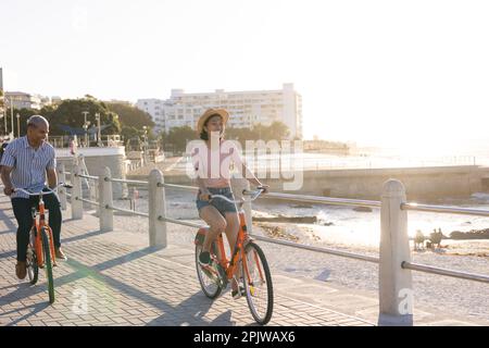 Heureux couple divers à vélo le long de la promenade au bord de la mer Banque D'Images