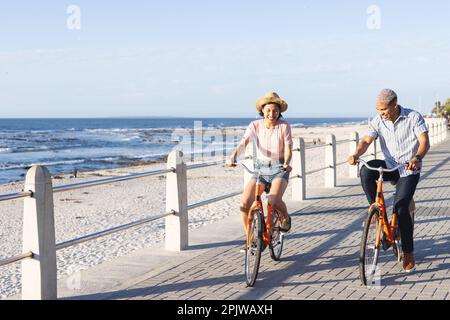 Heureux couple divers à vélo le long de la promenade au bord de la mer Banque D'Images