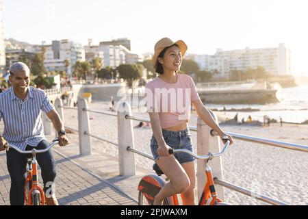 Heureux couple divers à vélo le long de la promenade au bord de la mer Banque D'Images