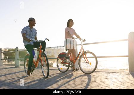 Heureux couple divers à vélo le long de la promenade au bord de la mer Banque D'Images