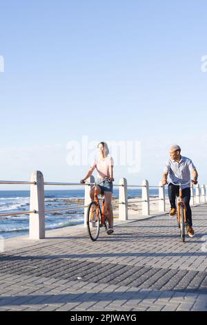 Heureux couple divers à vélo le long de la promenade au bord de la mer Banque D'Images