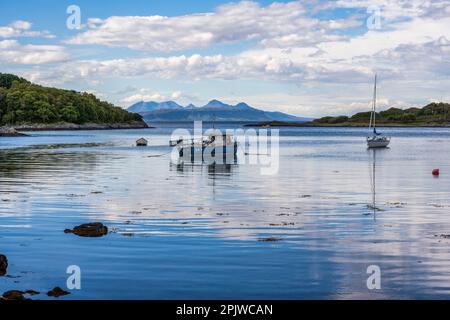 Bateaux amarrés dans la baie de Samalaman, avec l'île d'Eigg à distance et les montagnes de Rum au-delà, à Glenuig sur la péninsule d'Ardnamurchan à Lochaber, en Écosse Banque D'Images