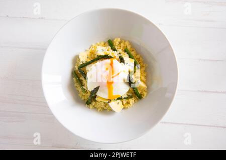 Plat au couscous avec un œuf frit, des asperges vertes et du fromage bleu. Banque D'Images