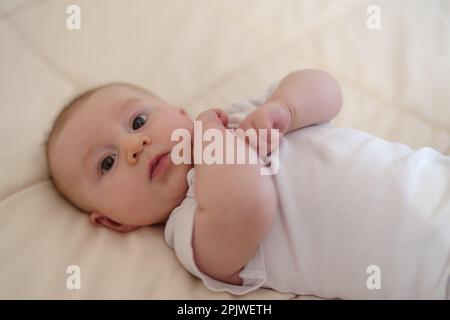 Un bébé de 3 mois allongé sur un lit Banque D'Images