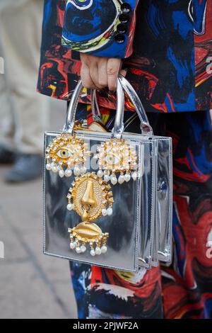 MILAN, ITALIE - 25 FÉVRIER 2023: Femme avec sac d'argent avec des détails de visage doré avant le spectacle de mode Missoni, Milan Fashion week Street style Banque D'Images