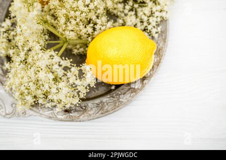 Tranches de citron frais dans une assiette en bois. Ingrédients pour le thé à base de plantes à base de sirop ancien. Des tiges d'ambucus très fines prêtes à préparer une boisson fraîche d'été Banque D'Images