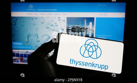 Personne tenant un smartphone avec le logo du conglomérat allemand ThyssenKrupp AG à l'écran devant le site. Mise au point sur l'affichage du téléphone. Banque D'Images
