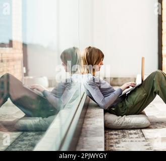 Un magnifique influenceur sur les médias sociaux des adolescents assis sur le patio à l'aide d'un ordinateur portable pour étudier et se divertir Banque D'Images