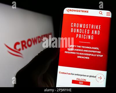 Personne tenant un téléphone cellulaire avec la page Web de la société de cybersécurité CrowdStrike Holdings Inc. À l'écran avec logo. Concentrez-vous sur le centre de l'écran du téléphone. Banque D'Images