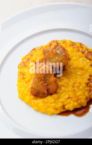 Un plat de risotto au safran accompagné de nuggets de poulet frits. Banque D'Images
