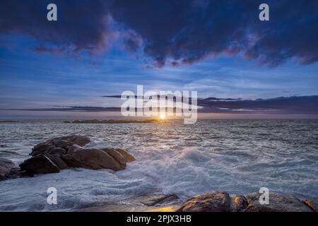 Coucher de soleil sur quelques récifs battus par les vagues sur la côte galicienne d'Espagne avec de lourds nuages d'eau Banque D'Images