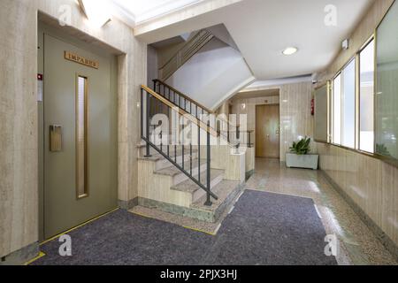 Portail intérieur d'un immeuble résidentiel avec moquette au sol et carreaux de marbre à côté des escaliers et de l'ascenseur Banque D'Images