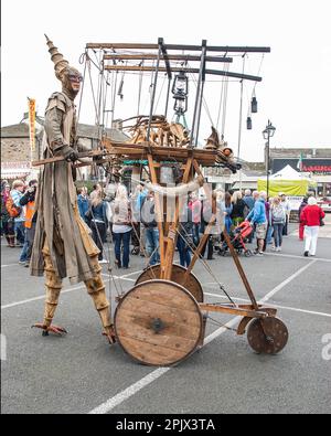 Personne sur pilotis avec une contre-mesure mobile qui porte un dragon enflamma, vu au festival international de marionnettes de Skipton vers 2015. Banque D'Images