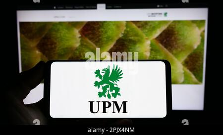 Personne tenant un smartphone avec le logo de la société forestière finlandaise UPM-Kymmene Oyj à l'écran devant le site Web. Mise au point sur l'affichage du téléphone. Banque D'Images