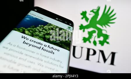 Smartphone avec page Web de la société forestière finlandaise UPM-Kymmene Oyj à l'écran devant le logo de l'entreprise. Faites la mise au point dans le coin supérieur gauche de l'écran du téléphone. Banque D'Images