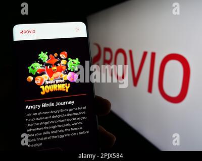 Personne tenant le téléphone portable avec la page web de la société finlandaise de jeux Rovio Entertainment Oyj à l'écran avec logo. Concentrez-vous sur le centre de l'écran du téléphone. Banque D'Images