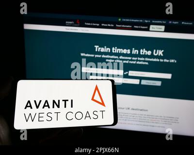 Personne tenant un smartphone avec le logo de la compagnie de train britannique Avanti West Coast sur l'écran devant le site Web. Mise au point sur l'affichage du téléphone. Banque D'Images