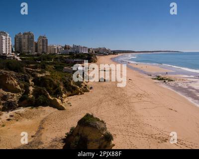 Vue le long des sables dorés de Praia de Vale Olival plage à la haute élévation de l'hôtel bâtiments Armação de Pêra Algarve Portugal eu avec les gens faisant le Banque D'Images