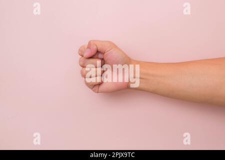 Main mâle avec geste de poing isolé sur fond rose. Poing fermé mâle. Banque D'Images