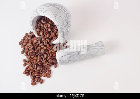 grains de café torréfiés naturels dans un mortier de marbre blanc isolé sur un fond blanc Banque D'Images