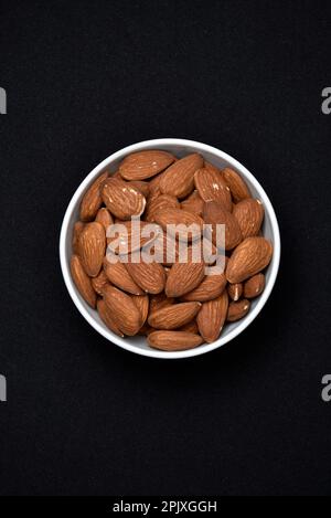 Amandes dans un bol en céramique blanche. Gros plan sur de délicieuses noix d'amandes. Banque D'Images