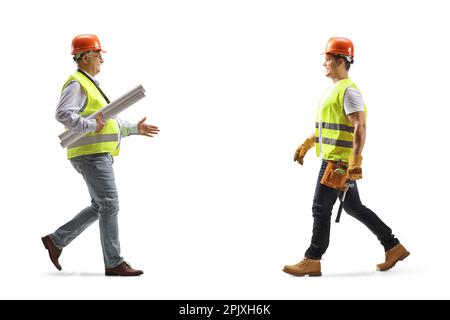 Prise de vue en profil d'un ingénieur portant des plans et accueillant un travailleur de la construction isolé sur fond blanc Banque D'Images