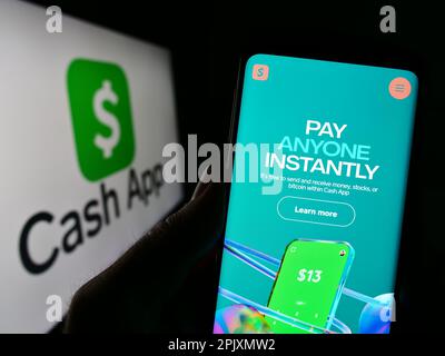 Personne tenant un smartphone avec la page Web de la société US fintech Cash App Investing LLC à l'écran devant le logo. Concentrez-vous sur le centre de l'écran du téléphone. Banque D'Images