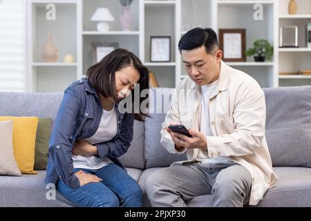 Couple de famille homme et femme assis sur un canapé à la maison asiatique homme de famille essayant d'appeler médecin pour femme malade. Banque D'Images