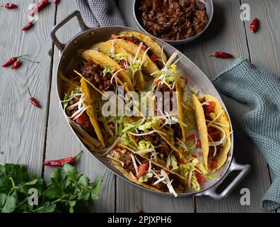 Tacos avec du bœuf cuit lentement, du fromage, des tomates et de la laitue dans un plat à rôtir à l'ancienne Banque D'Images