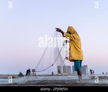 karachi pakistan 2021, un pêcheur portant une veste jaune préparant un filet de pêche pour la pêche en vue de la mer en soirée. Banque D'Images