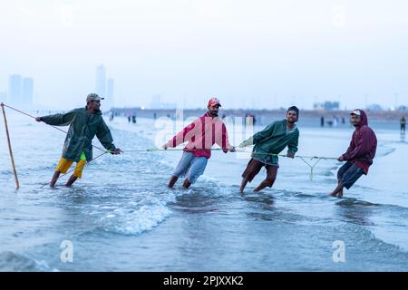 karachi pakistan 2021, un pêcheur tirant le filet de pêche pour attraper du poisson, en vue sur la mer en soirée. Banque D'Images