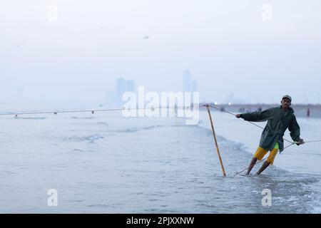 karachi pakistan 2021, un pêcheur tirant le filet de pêche pour attraper du poisson, en vue sur la mer en soirée. Banque D'Images