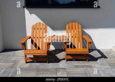 Deux chaises en bois reliées par une petite table en face d'une maison. Banque D'Images