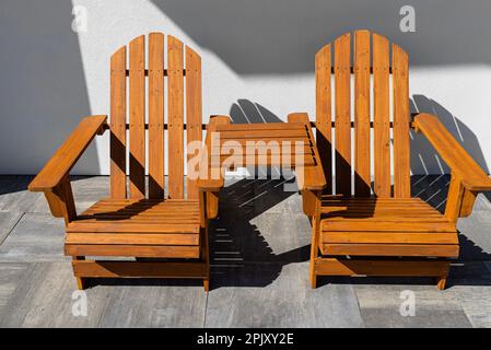 Deux chaises en bois reliées par une petite table en face d'une maison. Banque D'Images