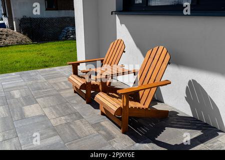 Deux chaises en bois reliées par une petite table en face d'une maison. Banque D'Images