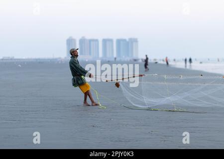 karachi pakistan 2021, un pêcheur tirant le filet de pêche pour attraper du poisson, en vue sur la mer en soirée. Banque D'Images