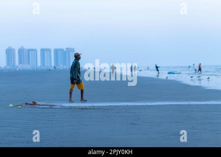 karachi pakistan 2021, un pêcheur tirant le filet de pêche pour attraper du poisson, en vue sur la mer en soirée. Banque D'Images