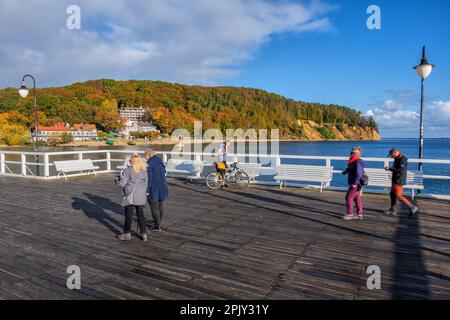 Personnes sur le quai en bois d'Orlowo sur la mer Baltique à Gdynia, Pologne avec vue sur la falaise d'Orlowski en automne. Banque D'Images