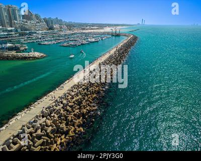 Vue aérienne d'un quai construit de rochers surplombant un océan baigné de soleil par une journée claire et ensoleillée Banque D'Images