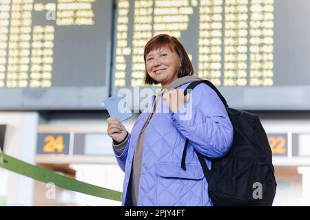 Femme adulte voyageant avec des bagages à main, sac à dos tient le passeport et attend le voyage de vol à l'aéroport international terminal. Femme d'âge moyen Go Banque D'Images