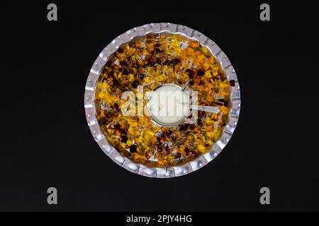 pudding au riz doux dans l'intestin argenté décoré de pétales de fleurs et d'un fond noir Banque D'Images