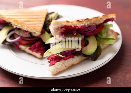 Pain plat grillé avec houmous de betteraves, tomates et avocats Banque D'Images