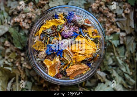 Séchez les feuilles de fleurs et de tisanes dans un pot en verre. Tisane de camomille, de fleur de maïs, de menthe, d'argousier, de citronnelle, rose sauvage, agrumes séchés Banque D'Images