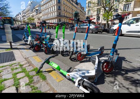 Location de scooters électriques auprès de diverses sociétés garées sur le côté de la route dans le quartier des champs-Elysées de Paris, France Banque D'Images