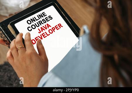 Concept d'apprentissage en ligne. Une femme tient une tablette dans ses mains sur l'écran dont il est écrit - cours en ligne JAVA développeur Banque D'Images